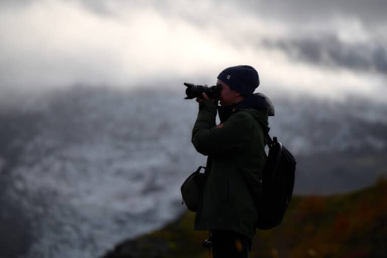 photographer silhouette with glacier in background and clouds